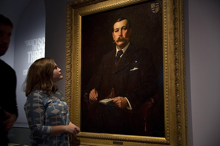 A Museum of London employee poses for photographers next to an 1897 oil on canvas portrait of Sherlock Holmes author Sir Arthur Conan Doyle by illustrator Sidney Paget on display as part of the exhibition "Sherlock Holmes: The Man Who Never Lived and Will Never Die" at the Museum of London in London, Oct. 16, 2014. Sherlock Holmes is finally free to the public in 2023. The long dispute on contested copyright on Doyle's tales of a whip-smart detective will come to an end in 2022, as the final Sherlock Holmes stories by Doyle will be released on Saturday, Dec. 31, as copyrights from 1927 expire on Jan. 1, 2023. (Matt Dunham/AP)