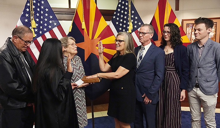 The new Arizona Democratic Gov. Katie Hobbs, middle, takes the oath of office in a ceremony as U.S. Circuit Judge for the Ninth Circuit Court of Appeals Roopali Desai, second from left, administers the oath while mother Linda Hobbs, third from left, holds the bible, and father John Hobbs, left, husband Patrick Goodman, third from right, daughter Hannah and son Sam, right, all look on at the state Capitol in Phoenix, Monday, Jan. 2, 2023.