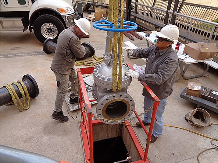 Reclamation personnel Damion Thomas (left) and Randolph Sloan (right) prepare to lower a valve down into what is referred to as a vault, where the valve will tap into two bypass tubes to construct a lower water supply for the nearby communities. (Photos/Bureau of Reclamation)