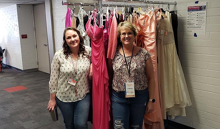 Sarah Garrett (left) and Lynette Prouty (right) posing in front of clothing rack at Project Prom Closet, which brings new or lightly used formalwear to Cottonwood for those who might not otherwise be able to afford to go to Prom. (Photo courtesy of Rotary Club of the Verde Valley)
