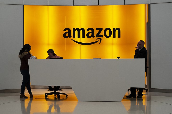 In this Feb. 14, 2019 file photo, people stand in the lobby for Amazon offices in New York. Amazon is ending a charity donation program it ran for a decade in its latest cost-cutting move. In a blog post on Wednesday, Jan. 18, 2023, the company said the program, called AmazonSmile, will shut down by February 20. (Mark Lennihan/AP, File)
