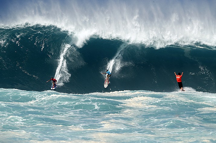 Kai Lenny, left, and Aaron Gold, center, are cheered on by Jake Maki, right, in Hawaii's Waimea Bay on Oahu’s North Shore during the The Eddie Aikau Big Wave Invitational surfing contest Sunday, Jan. 22, 2023. (Jamm Aquino/Honolulu Star-Advertiser via AP)