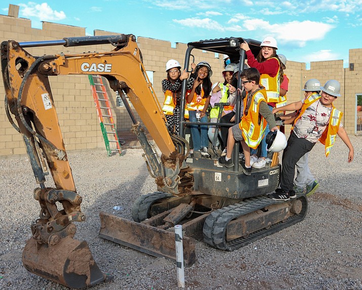 TradeUp! students climb on a mini excavator – while it’s turned off – to see what the buttons and switches do. Photo taken Nov. 1, 2022, at Madison Park Middle School in Phoenix. (Justin Spangenthal/Cronkite News)