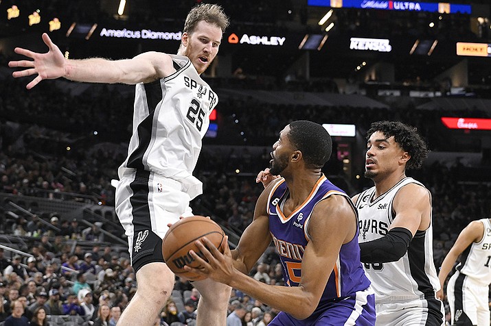 Phoenix Suns' Mikal Bridges, center, looks to pass the ballas he is defended by San Antonio Spurs' Jakob Poeltl (25) and Tre Jones during the second half of an NBA basketball game, Saturday, Jan. 28, 2023, in San Antonio. (Darren Abate/AP)