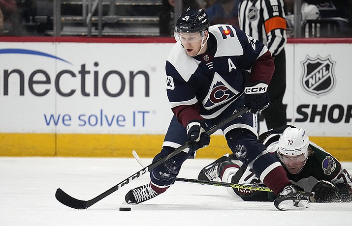 Colorado Avalanche center Nathan MacKinnon, front, collects the puck against Arizona Coyotes center Travis Boyd in the second period of an NHL hockey game, Saturday, March 11, 2023, in Denver. (David Zalubowski/AP)