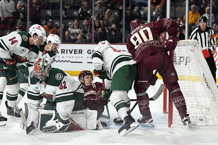 Arizona Coyotes right wing Clayton Keller scores a goal in overtime surrounded by defenseman J.J. Moser (90), Minnesota Wild center Joel Eriksson Ek (14), goaltender Filip Gustavsson (32), and defenseman Jared Spurgeon (46) during an NHL hockey game, Sunday, March 12, 2023, in Tempe, Ariz. Arizona won 5-4 in overtime. (Rick Scuteri/AP)