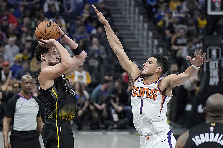Golden State Warriors guard Klay Thompson, left, makes a 3-point basket against Phoenix Suns guard Devin Booker (1) during the first half of an NBA basketball game in San Francisco, Monday, March 13, 2023. (Jeff Chiu/AP)