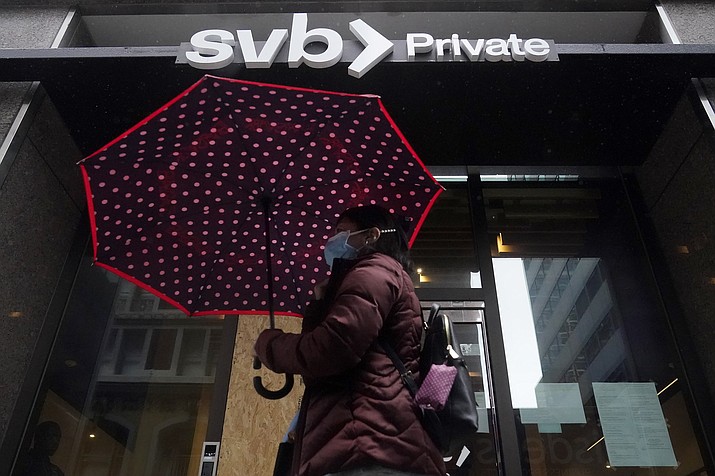 A pedestrian carries an umbrella while walking past a Silicon Valley Bank Private branch in San Francisco, Tuesday, March 14, 2023. After a frenetic weekend of round-the-clock briefings, U.S. policymakers took the audacious step guaranteeing all the deposits of the failed Silicon Valley Banks, even those exceeding the FDIC's $250,000 limit. (Jeff Chiu/AP)