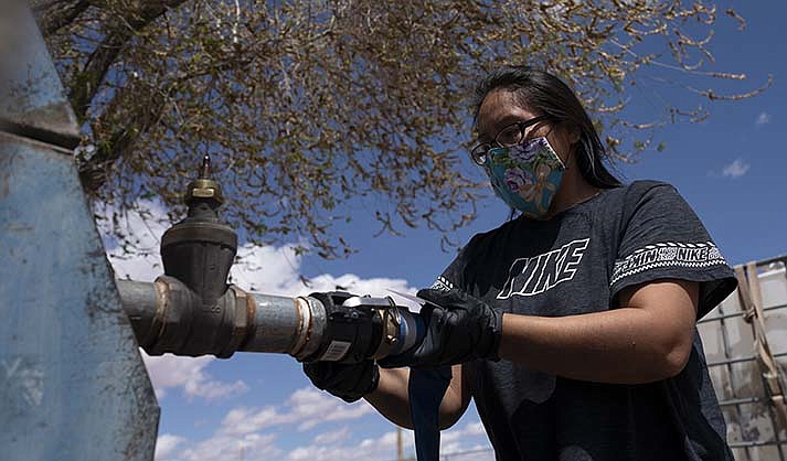 Raynelle Hoskie attaches a hose to a water pump to fill tanks in her truck outside a tribal office on the Navajo reservation in Tuba City on April 20, 2020.(AP Photo/Carolyn Kaster, File)