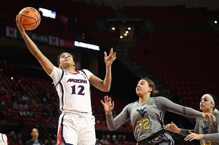 Arizona forward Esmery Martinez (12) goes to the basket past West Virginia guard Kyah Watson (32) and forward Isis Beh, right, in the first half of a first-round game in the NCAA Tournament, Friday, March 17, 2023, in College Park, Md. (Nick Wass/AP)
