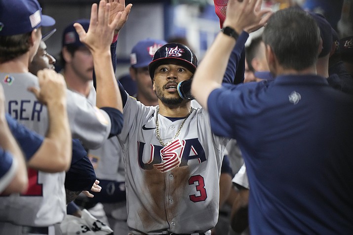 United States' Mookie Betts (3) is congratulated by teammates after he scored on a throwing error by Venezuela center fielder Ronald Acuna Jr., during the first inning of a World Baseball Classic game, Saturday, March 18, 2023, in Miami. (Wilfredo Lee/AP)