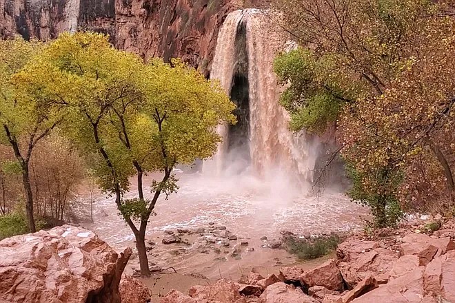 The blue-green water fall in Supai, Arizona turned muddy in 2019 floods. On Mary 17, destructive flooding in Supai Canyon led to the evacuation of the Havasupai Campground. (Photo/ Shannon Castellano via AP)