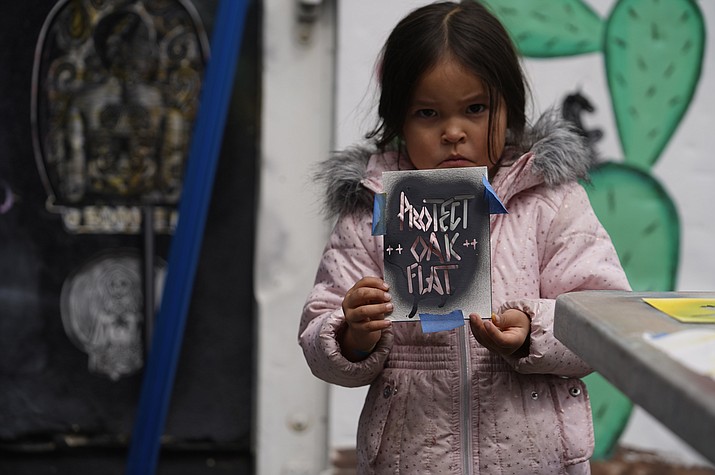 Apache Stronghold member Raetana Manny, 4, shows a sign to save Oak Flat, a site east of Phoenix that the group considers sacred, as she joined a gathering at Self Help Graphics & Art in the Los Angeles neighborhood of Boyle Heights on Monday, March 20, 2023. The Apache group battling a foreign mining firm that wants to build one of the largest copper mines in the United States on what tribal members say is sacred land will get a new chance to make its point Tuesday when a full federal appeals court panel takes another look at the case. (Damian Dovarganes/AP)