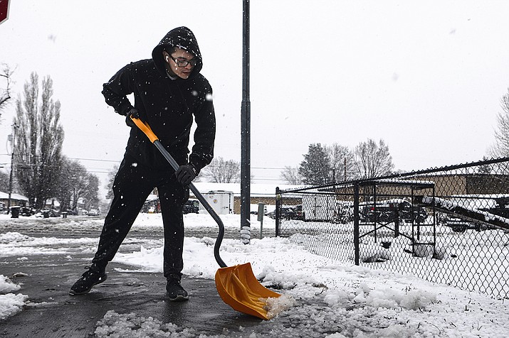 Jovany Martinez shovels the sidewalk around his Sunnyside home as snow falls yet again on Flagstaff, Ariz., early Tuesday, March 21, 2023. Some residents of north-central Arizona were told to prepare to evacuate Tuesday afternoon because of rising water levels in rivers and basins. (Rachel Gibbons/Arizona Daily Sun via AP)