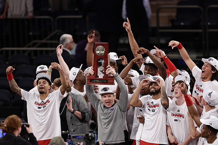 Florida Atlantic head coach Dusty May holds up the trophy as Florida Atlantic players celebrate after defeating Kansas State in the second half of an Elite 8 college basketball game in the NCAA Tournament's East Region final, Saturday, March 25, 2023, in New York. (Adam Hunger/AP)