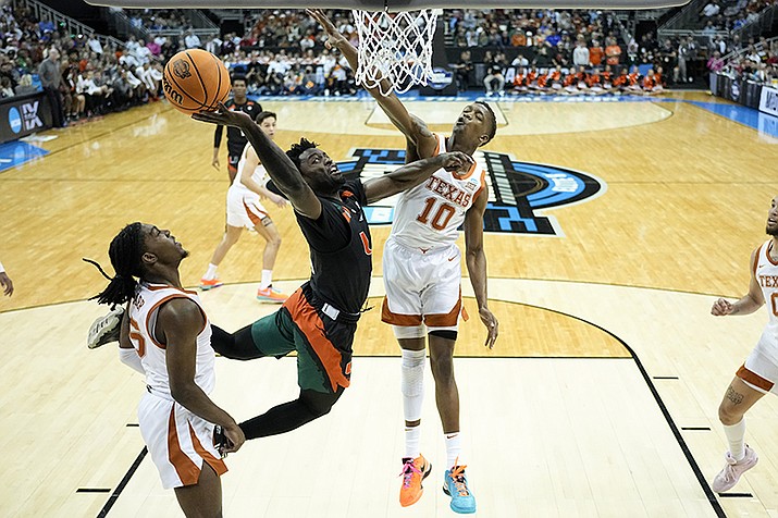 Miami guard Bensley Joseph drives to the basket past Texas guard Sir'Jabari Rice and guard Marcus Carr, left, in the first half of an Elite 8 college basketball game in the Midwest Regional of the NCAA Tournament Sunday, March 26, 2023, in Kansas City, Mo. (Jeff Roberson/AP)