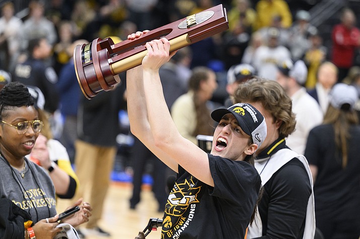 Iowa guard Caitlin Clark shows off the trophy as she celebrates after an Elite 8 game of the NCAA Tournament against Louisville, Sunday, March 26, 2023, in Seattle. Iowa won 97-83. (Caean Couto/AP)