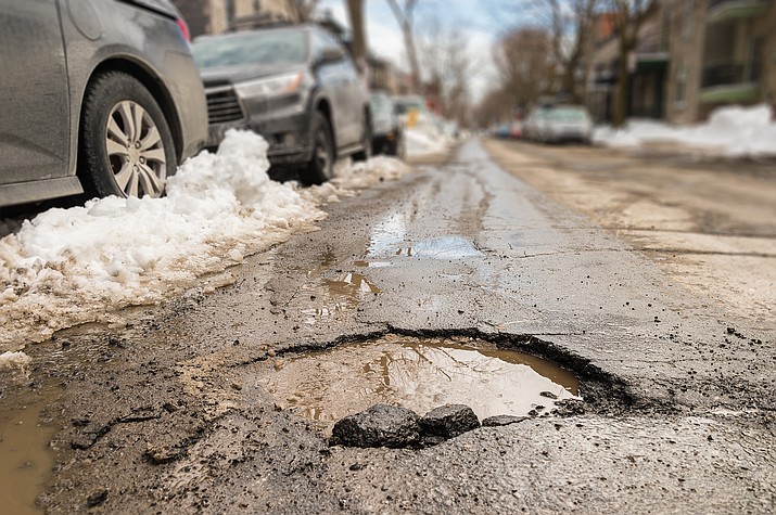 Wet and snowy weather in Arizona has caused an increase in potholes, with ADOT urging drivers to slow down and report pavement issues. (Photo/Adobe Stock)