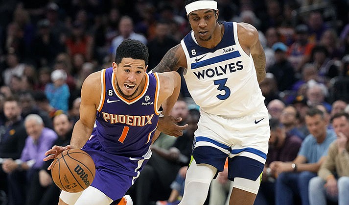 Phoenix Suns guard Devin Booker (1) drives past Minnesota Timberwolves forward Jaden McDaniels (3) during the second half of an NBA basketball game Wednesday, March 29, 2023, in Phoenix. The Suns won 107-100. (AP Photo/Ross D. Franklin)