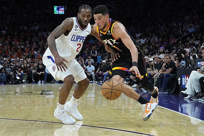 Phoenix Suns guard Devin Booker (1) drives on Los Angeles Clippers forward Kawhi Leonard (2) during the second half of Game 2 of a first-round NBA basketball playoff series, Tuesday, April 18, 2023, in Phoenix. (AP Photo/Matt York)
