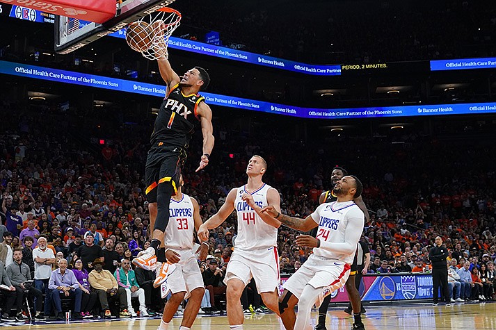 Phoenix Suns guard Devin Booker (1) dunks over Los Angeles Clippers center Mason Plumlee (44), forward Nicolas Batum (33), and guard Norman Powell (24) during the second half of Game 5 of a first-round NBA basketball playoff series, Tuesday, April 25, 2023, in Phoenix. (AP Photo/Matt York)