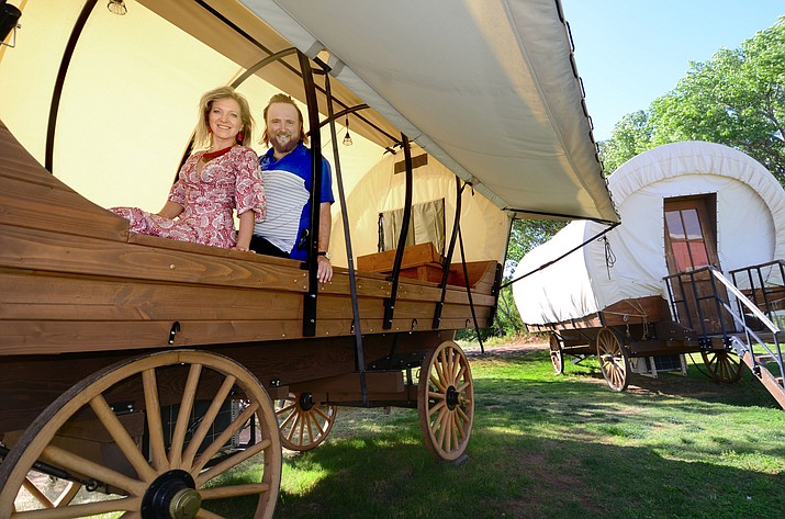 Ryan and Leila Glass pose in a wagon at Blazin’ M Ranch, which will be getting 11 Conestoga wagon guest units in their newly approved glamping area. They will be similar to this one, which is their display model. (VVN/Vyto Starinskas)