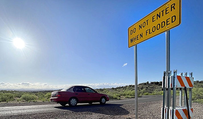 Saw-horse type barriers hang on a flood warning sign on Camino Real/SR279 on Thursday, May 4, 2023, to be used at the wash crossing in case of flooding where Faith Moore drove across on July 24, 2021. (VVN/Vyto Starinskas)