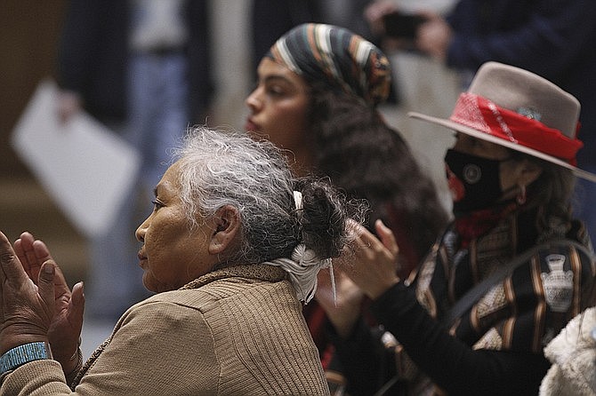 Demonstrators, including Katherine Benally of Ya-Ta-Hey, N.M., foreground, applaud speakers at a demonstration against the appointment of James Mountain to lead the New Mexico Indian Affairs Department, at the New Mexico state Capitol building in Santa Fe, N.M. March 17, 2023.  (AP Photo/Morgan Lee)