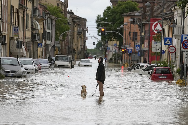 A man walks his dog along a flooded street in Castel Bolognese, Italy, Wednesday, May 17, 2023. Exceptional rains Wednesday in a drought-struck region of northern Italy swelled rivers over their banks, killing at least eight people, forcing the evacuation of thousands and prompting officials to warn that Italy needs a national plan to combat climate change-induced flooding. (Luca Bruno/AP)