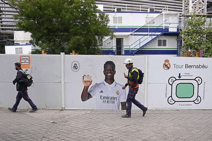 Workers pass a poster of Real Madrid's Vinicius Junior outside the Santiago Bernabeu stadium in Madrid, Spain, Monday, May 22, 2023. Spanish soccer is again embroiled in a racism debate after yet another case of abuse against Real Madrid forward Vinicius Junior, with the president of Spain's soccer federation acknowledging that the country has a racism problem and the player's club asking authorities to investigate the latest incident as a hate crime. (Paul White/AP)