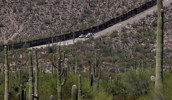 U.S. Customs and Patrol Patrol agents sit along a section of the international border wall that runs through Organ Pipe Cactus National Monument, Thursday, Aug. 22, 2019 in Lukeville. U.S. Border Patrol agents answering reports of gunfire shot and killed a man on a tribal reservation in southern Arizona after he abruptly threw something and raised his arm, the agency said Monday, May 22, 2023.  (AP Photo/Matt York, File)