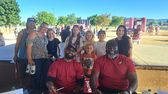 Former Arizona Cardinals players Michael Pittman, front left, and Leonard Davis, front right, pose for a picture with a family. (Debra Winters/Courier)
