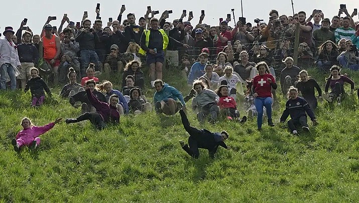 Participants compete in the women's downhill race during the Cheese Rolling contest at Cooper's Hill in Brockworth, Gloucestershire, Monday, May 29, 2023. The Cooper's Hill Cheese-Rolling and Wake is an annual event where participants race down the 200-yard-long hill chasing a wheel of double gloucester cheese. (AP Photo/Kin Cheung)