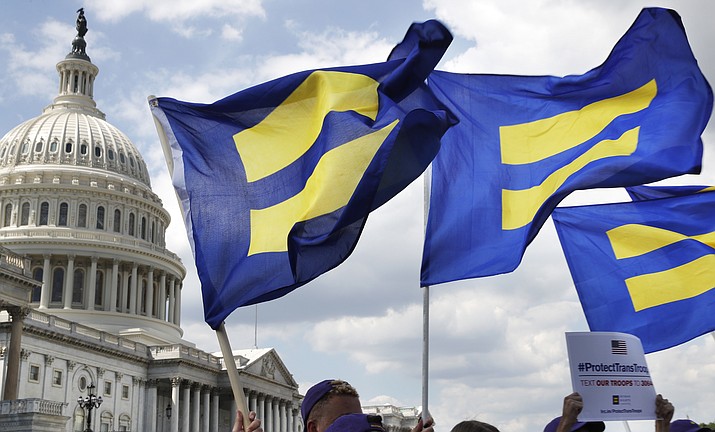 People with the Human Rights Campaign hold up "equality flags" during an event on Capitol Hill on July 26, 2017, in Washington, in support of transgender members of the military. The Human Rights Campaign declared a state of emergency for LGBTQ+ people in the U.S. on Tuesday, June 6, 2023, and a released “a guidebook for action” summarizing what it calls discriminatory laws in each state, along with “know your rights” information and health and safety resources. (Jacquelyn Martin/AP, File)