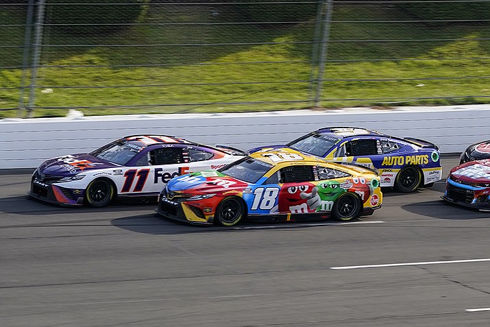 Denny Hamlin (11) and Kyle Busch (18) lead Chase Elliott (9), right, on a restart late in the NASCAR Cup Series auto race at Pocono Raceway, with Sunday, July 24, 2022, in Long Pond, Pa. Hamlin and Busch return to Pocono Raceway a year after they suffered disqualifications and had their 1-2 finishes thrown out. (Matt Slocum, AP File)