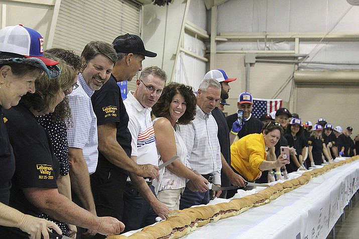 Volunteers help assemble the 150-foot-long (45.7-meters-long) bologna sandwich at the Lebanon Area Fair on Tuesday, July 25, 2023 in Lebanon, Pa. Every foot-long “bite” was sponsored at $100 per foot. The money was donated to Lebanon County Christian Ministries and their efforts to help people dealing with food insecurity in the Lebanon Valley. ( Daniel Larlham Jr. /Lebanon Daily News via AP)