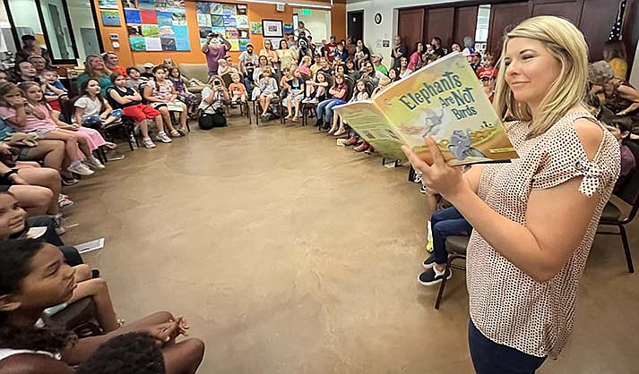 Children and adults listen to Sheila Backus read a book during the See You at the Library event at the Camp Verde Library on Saturday Aug. 5, 2023. (VVN/Vyto Starinskas)