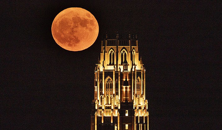 A supermoon rises over the West End Tower at Vanderbilt University, Aug. 1, 2023, in Nashville, Tenn. Stargazers are in for a double treat on Wednesday night, Aug. 30: a rare blue supermoon with Saturn peeking from behind. The cosmic curtain rises Wednesday night with the second full moon of August, the reason it’s considered blue. It’s dubbed a supermoon because it’s closer to Earth than usual, appearing especially big and bright. (AP Photo/George Walker IV, File)