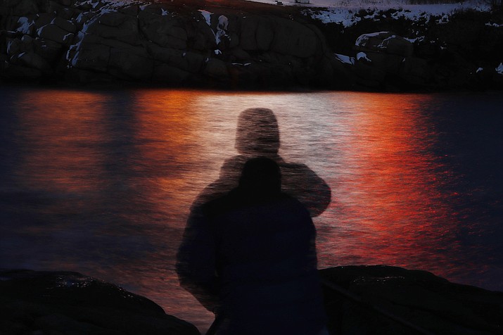 In this photo made with a long exposure, a man is silhouetted against lights reflected in the waters off Cape Neddick in Maine on Dec. 11, 2017. A study published Thursday, Sept. 14, 2023, in the journal Nature Medicine has found that the psychedelic drug MDMA, combined with talk therapy, can reduce symptoms of post-traumatic stress disorder. (Robert F. Bukaty/AP, File)