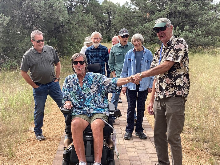 Brad Newman, front left, leads the way for his invitation-only “Welcome Home” ceremony at the Community Nature Center on Wednesday, Sept. 20, 2023. Longtime friend and center founder and volunteer Henry Dahlberg holds his hand as other friends and YEI clients follow behind. (Nanci Hutson/Courier)