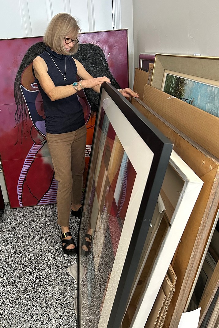 Local art enthusiast Jane Callaway sorts through paintings, identifying pieces to include in Art for Everyone. (Courtesy photo)