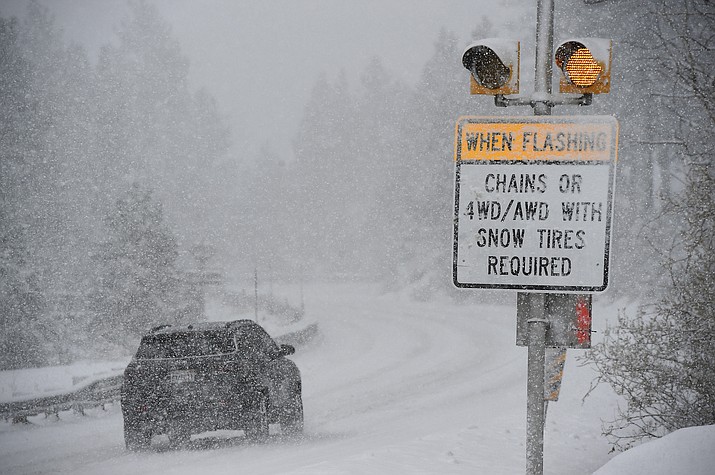 A car passes a caution sign as heavy snow falls on the Mt. Rose Highway near Reno, Nev., on Dec. 1, 2022. The National Weather Service issued advisories Saturday, Nov. 18, 2023, along the California-Nevada line ahead of an early winter storm that could bring more than a foot (30 centimeters) of snow to the upper elevations of the Sierra and winds gusting up to 100 mph (160 kph) over ridgetops. The winter weather advisories, in effect from 4 p.m. Saturday through 4 a.m. Sunday, stretched from the Lake Tahoe area near Reno to south of Yosemite National Park, including Mammoth Lakes, California. (Jason Bean/The Reno Gazette-Journal via AP, File)