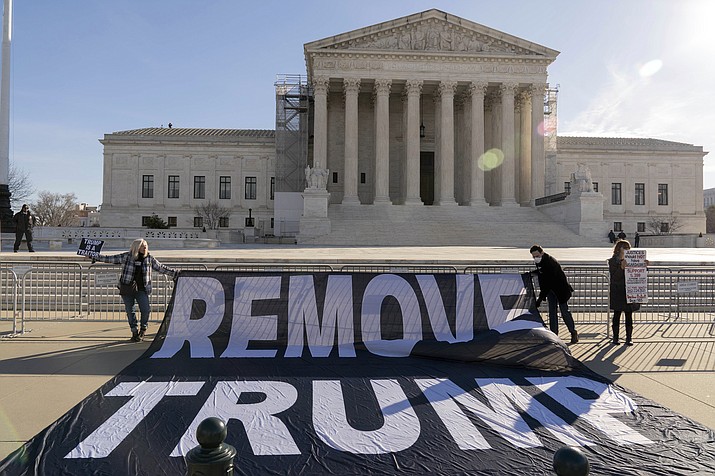 Demonstrators hold a banner outside of the U.S. Supreme Court, Thursday, Feb. 8, 2024, in Washington. The U.S. Supreme Court on Thursday will take up a historic case that could decide whether Donald Trump is ineligible for the 2024 ballot under Section 3 of the 14th Amendment. (Jose Luis Magana/AP)