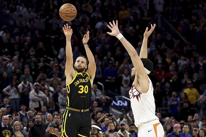 Golden State Warriors guard Stephen Curry (30) shoots a go-ahead basket against Phoenix Suns guard Devin Booker, right, during the second half in San Francisco, Saturday, Feb. 10, 2024. (Jed Jacobsohn/AP)