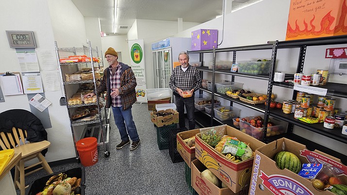David Hendrickson, employee, and Karl Frotzler, volunteer, sift through boxes and place items on the shelves of the Prescott Community Cupboard. (Debra Winters/Courier)