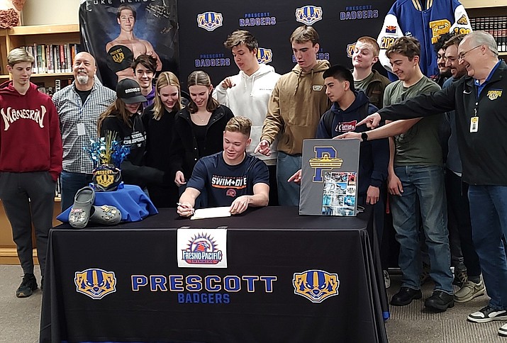 Luke Herbert of Prescott High School signs with Fresno Pacific University while surrounded by his Prescott teammates and coaches. (Thomas Staples/Courier)